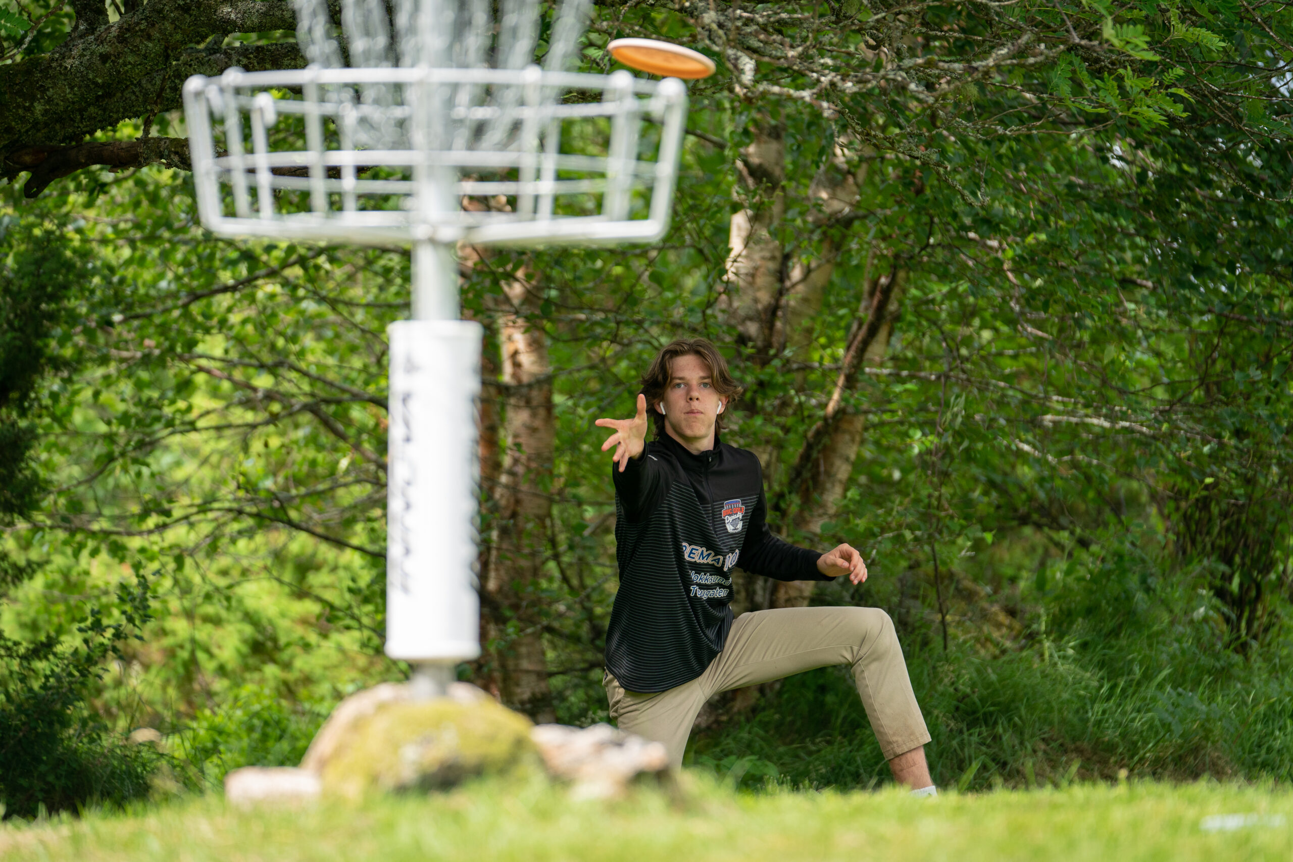 A European disc golfer putts from a knee.